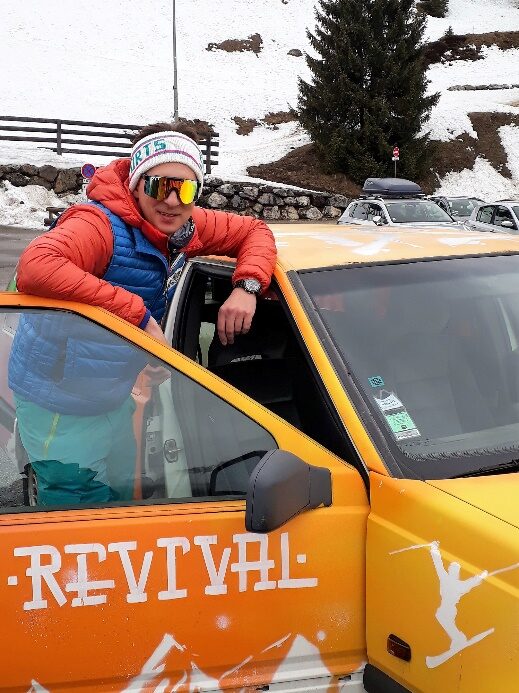 Lionel Lamberlin en doudoune orange, accoudé à la portière du van jaune floqué Revival
