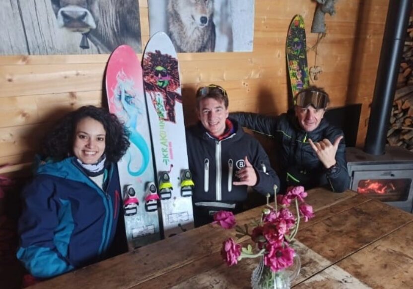 Trois membres de Silicone One attablés dans un chalet, leurs monoskis dressés derrière eux