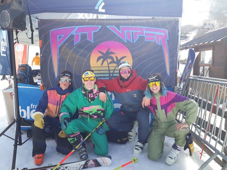 Quatre jeunes riders en combinaisons rétro colorées, accroupis devant un fond peint