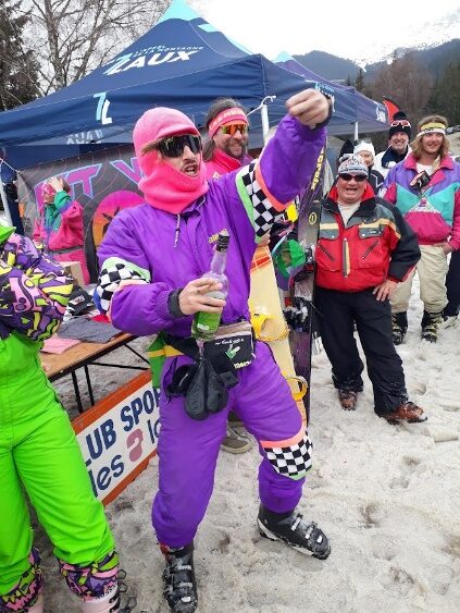 Riders en combinaisons violette et verte posant devant les stands du Revival